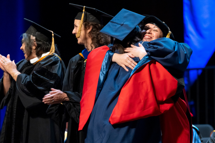 A credential student hugs Claudia Rodriguez-Mojica as they cross the stage.