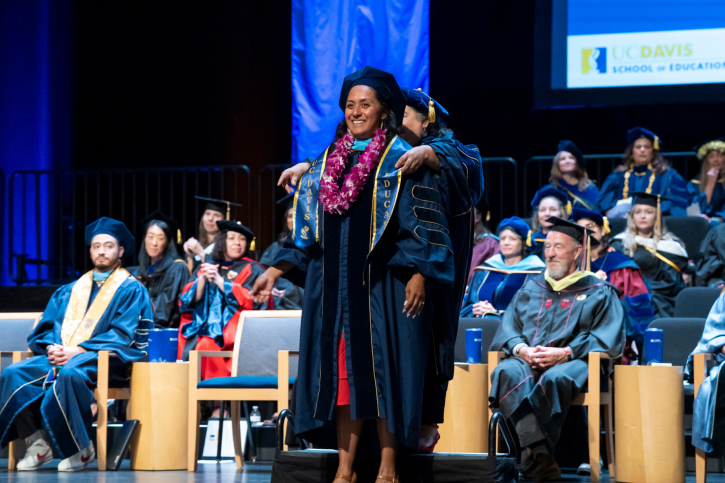 A doctoral student smiles as she receives her stole.