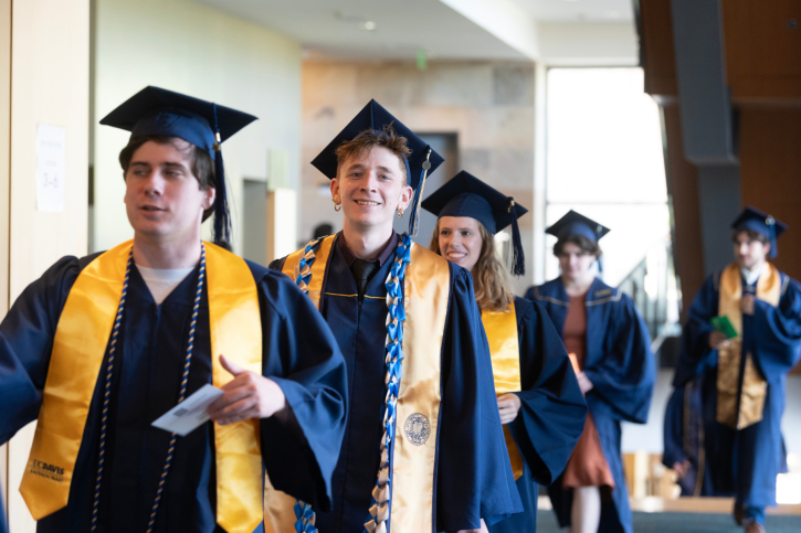 A line of science credential grads walk toward the entrance of Jackson Hall.
