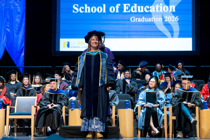 A doctoral grad smiles after receiving her stole.