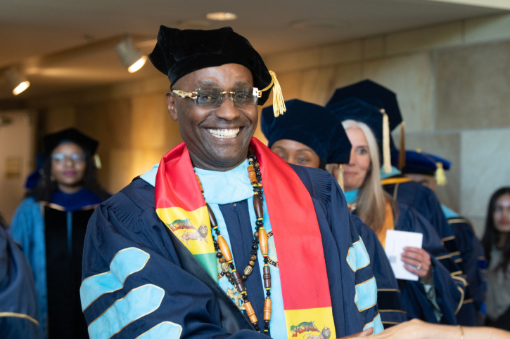 EdD grad Kayton smiles widely as he shakes someone's hand.