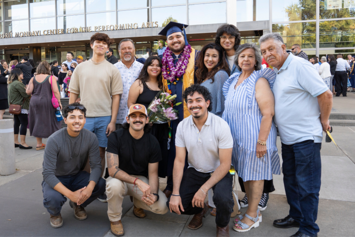 Credential grad Ezra smiles with friends and family.