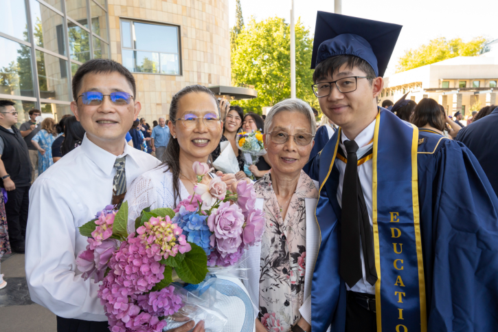 MA grad Alex smiles with family.
