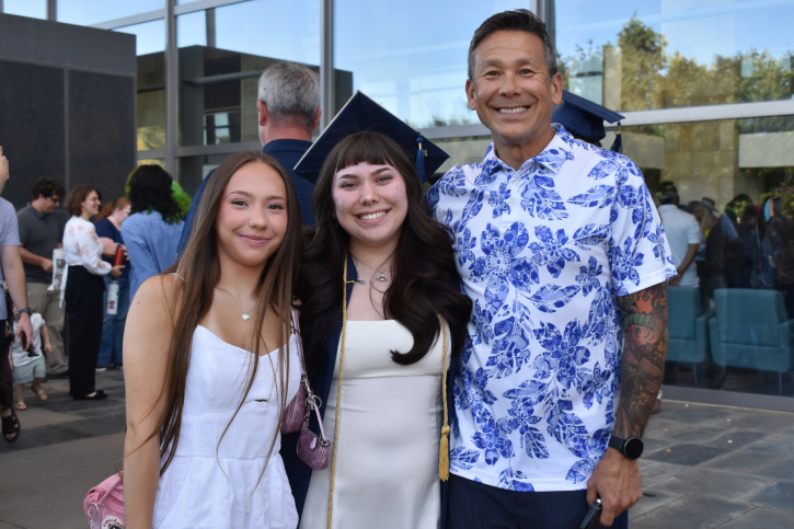 Credential grad Cai smiles with their family.