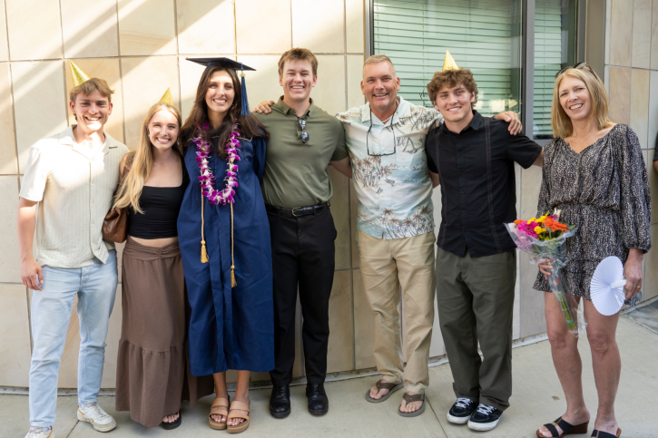 Credential grad Madison smiles with family, some of whom are wearing gold party hats.