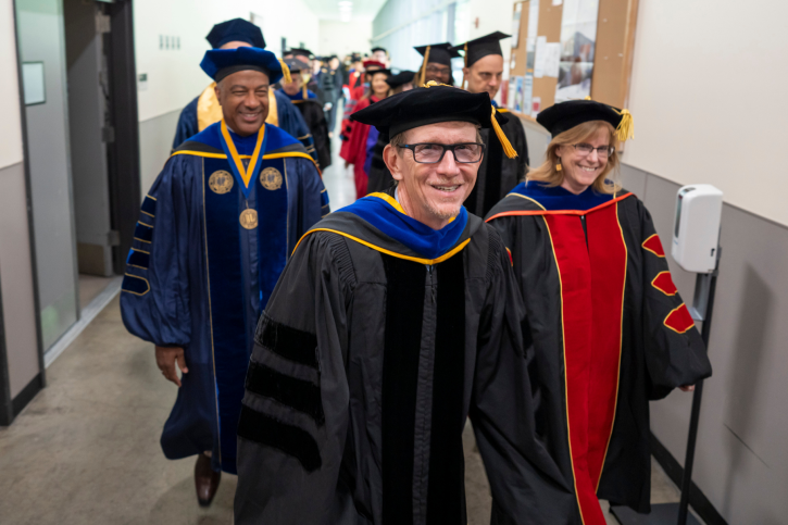 Dean Smith smiles alongside Dr. Cindy Passmore and Chancellor May as they walk toward Jackson Hall.