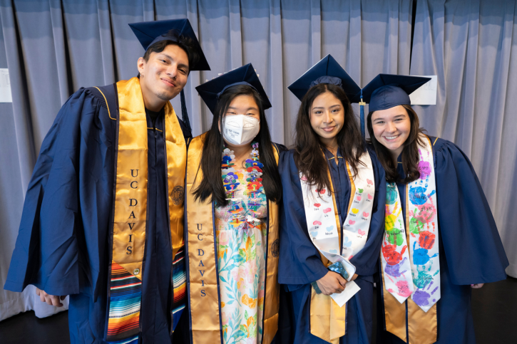 Scholarship recipients smile for the camera, wearing colorful stoles and navy gowns.