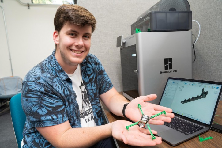 Adam holds up a 3-D model in the shape of an X