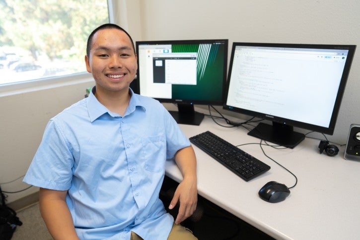 Student poses in front of computer