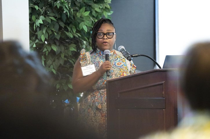 Alexis Patterson Williams addresses the newest teaching credential cohort while standing at a podium.