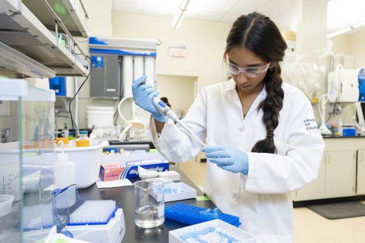 Avani fills a vial using a pipette.