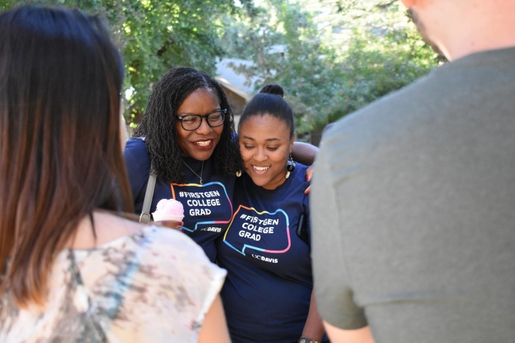 Professors hug each other while wearing FirstGen College Grad t-shirts