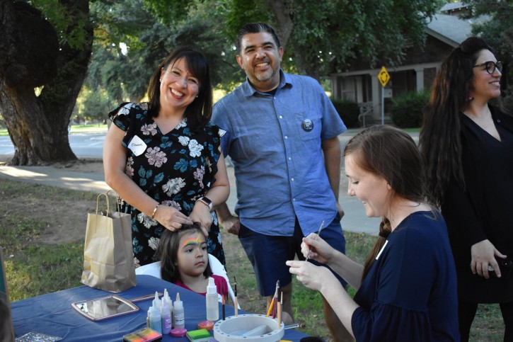 Elizabeth Montaño and Danny Martinez pose for camera as child gets face painted