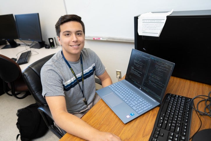 Student poses with laptop at desk