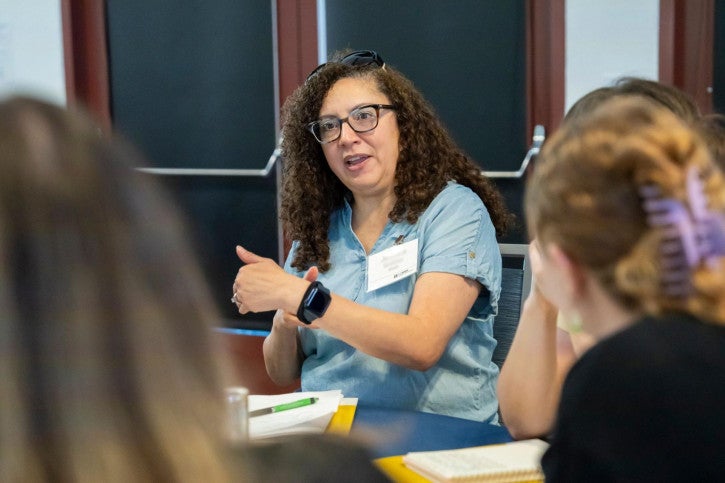 A credential student addresses the other people sitting at her table.