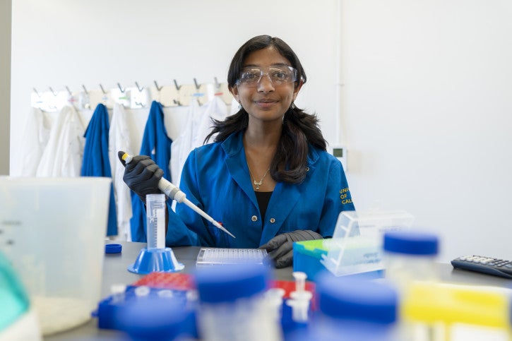 Hasini smiles for the camera, holding a pipette.