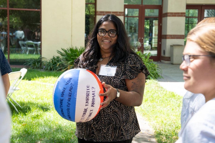 A credential student smiles and holds a beach ball in her hands.