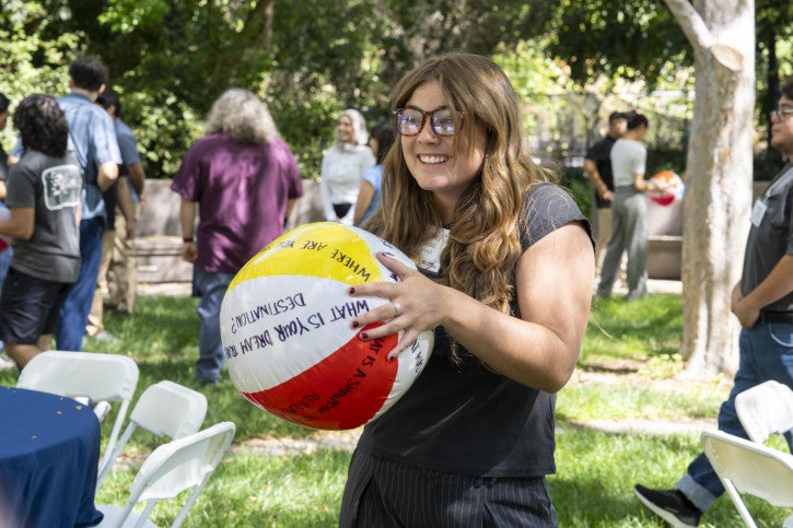 A credential student catches a beach ball with icebreaker questions written on it.