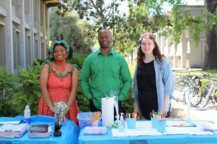 Darnel Degand poses with two booth volunteers.