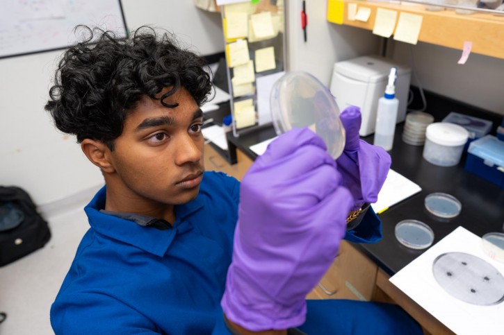 Josh holds up a petri dish to inspect it