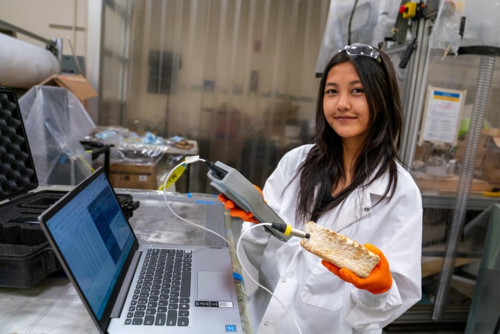 Lyka holds up equipment in the lab