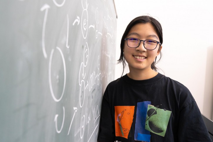 Nicole smiles next to a chalkboard