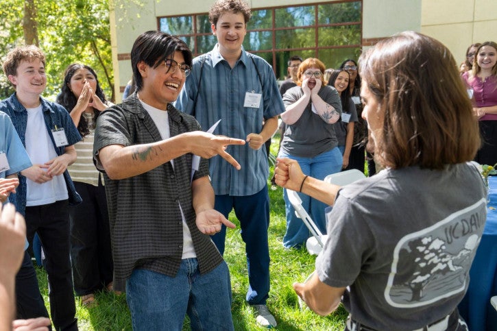 A large crowd of credential students gather around to face off in Rock, Paper, Scissors.