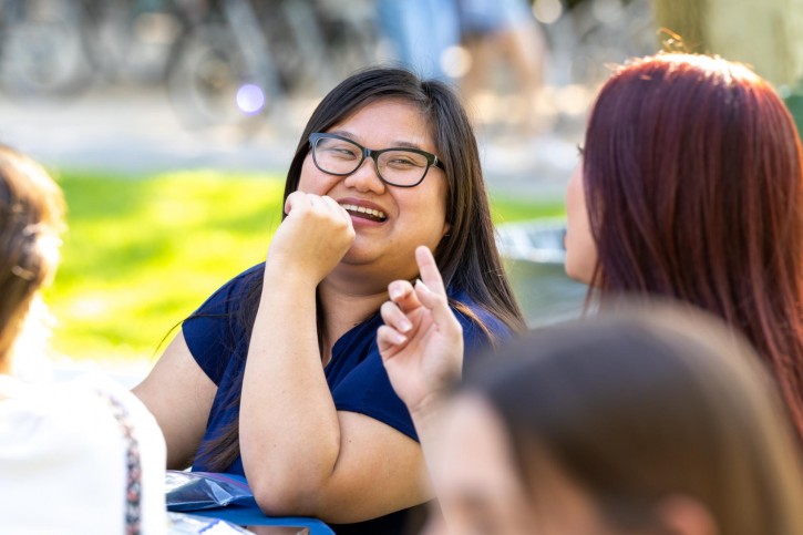 A woman with glasses smiles at her friend