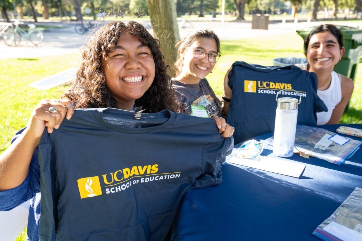 Students hold up their School of Education t-shirts