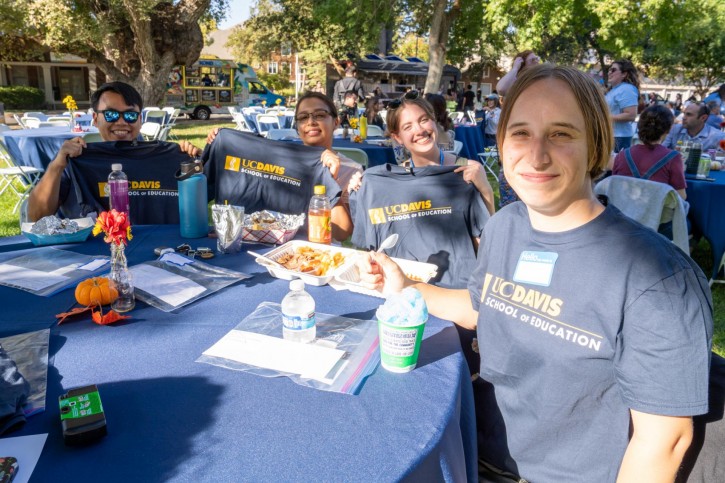 Teacher education students sit at a table and smile for the camera