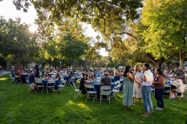 Wide shot of people at tables on Olson lawn