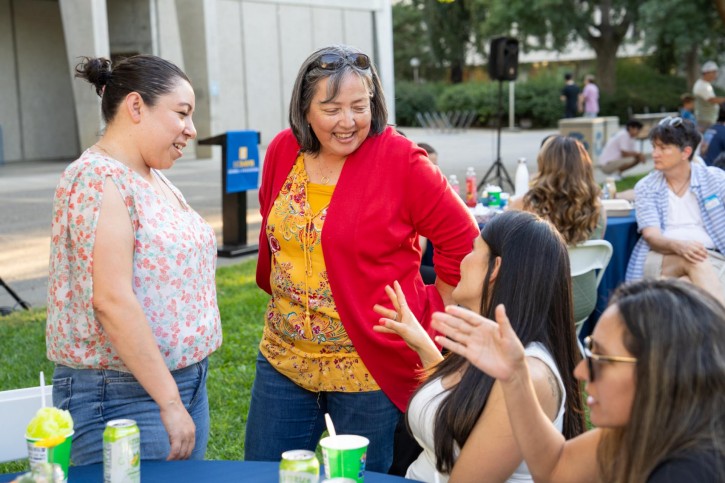 Faculty members talk to people at a table