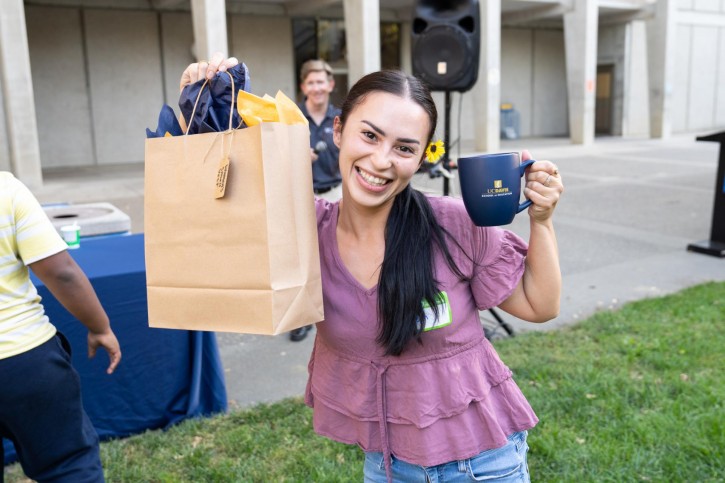 An attendee holds up her raffle prizes: a gift bag and a mug.