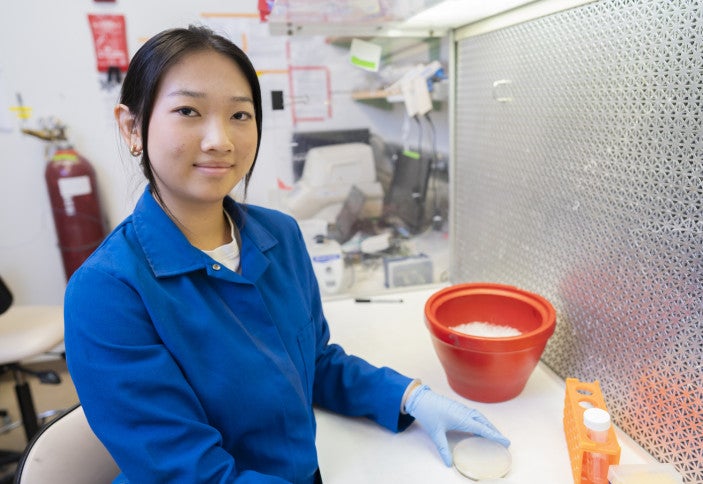 Wendy sits at the lab bench and smiles.