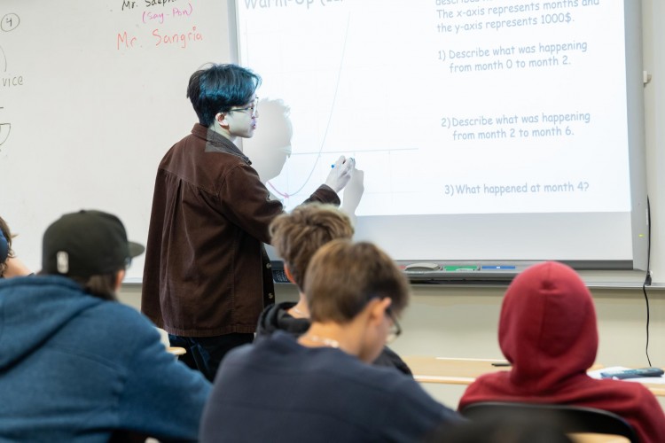 A male teacher draws a graph on the board.