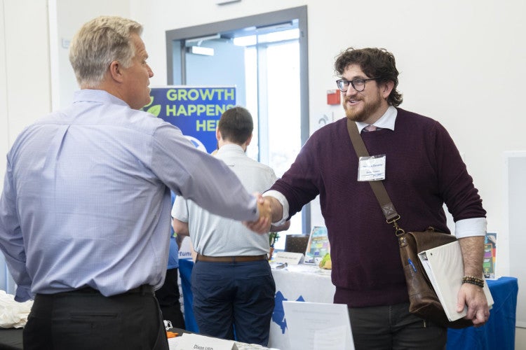 A school district representative shakes hands with a credential student.