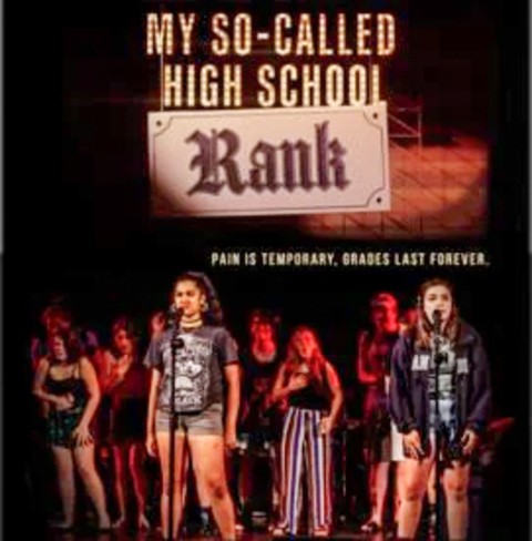 A group of young people sing on a stage beneath a sign that reads 'MY SO-CALLED HIGH SCHOOL RANK: Pain is temporary, grades are forever'