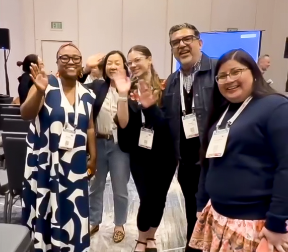 Faculty members, students, and alumni smile and wave at the 2026 AERA Conference.