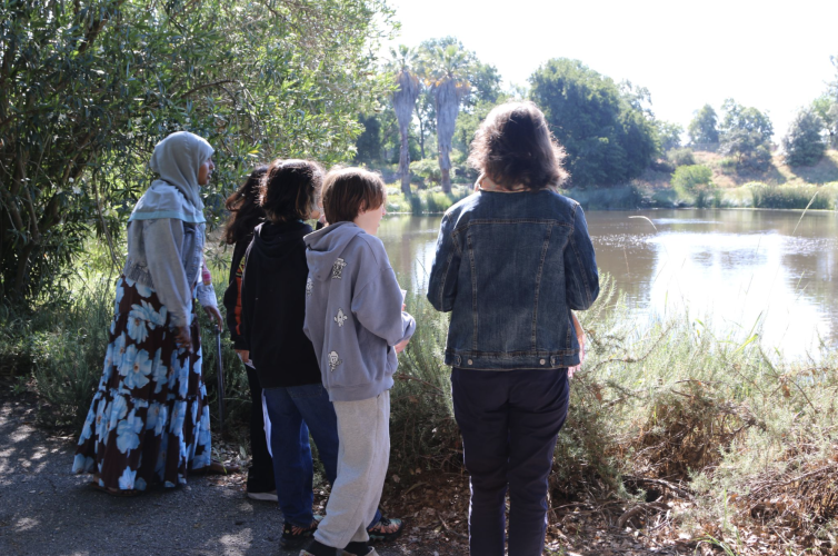 A paraeducator with students observing the Arboretum waterway.