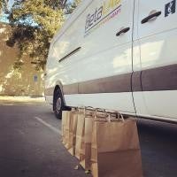 Five grocery paper bags are lined up in a row outside the Beta Lab van.