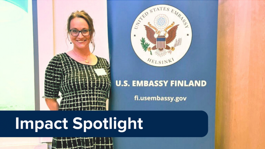 Cristina Buss stands next to a banner for the U.S. Embassy in Helsinki, Finland