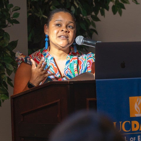 Close up of a woman standing at a podium, speaking into a microphone.