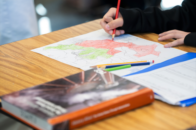 Close-up of a student's hand coloring in a region on a US map.