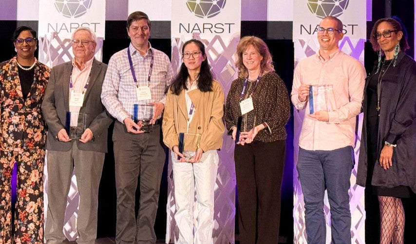 The research team stands on stage at the NARST 2026 Conference and holds awards in their hands.