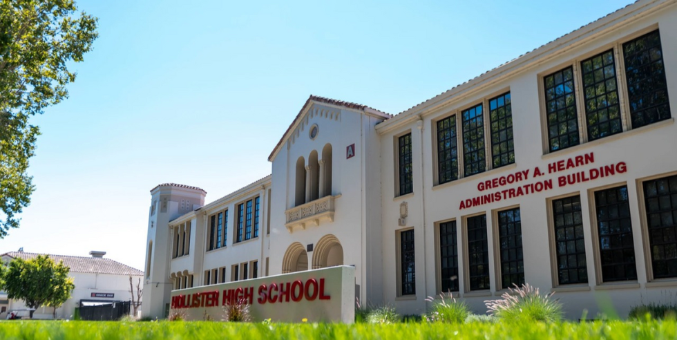 A large white building with a cement sign out front that reads "Hollister High School"