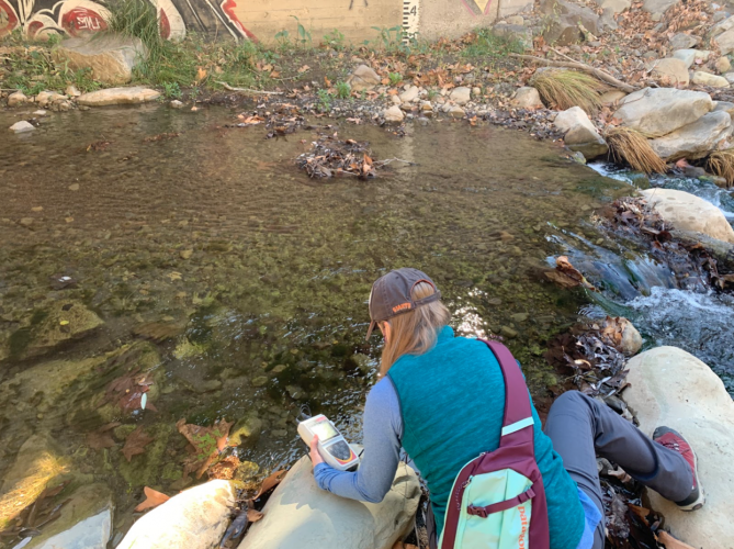 person using an electronic monitor at a creek