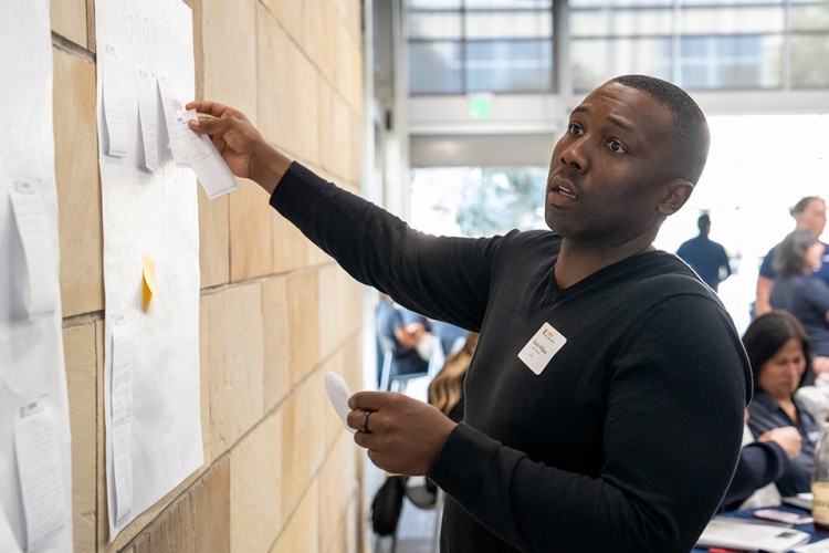 Charles Wilkes adding a sticky note to a wall in a retreat