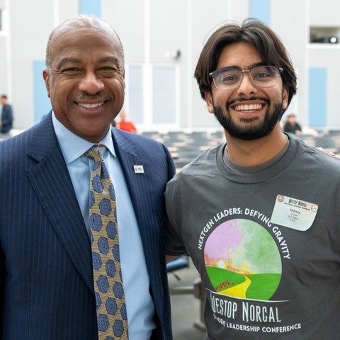 A young man poses for a photo with Chancellor Gary S. May