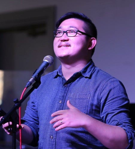 Yiwang Li speaks into a microphone and looks up in front of him.