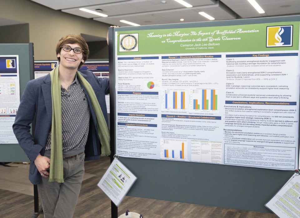 A master's candidate stands next to his research poster titled "Meaning in the Margins: The Impact of Scaffolded Annotation on Comprehension in the 6th Grade Classroom."